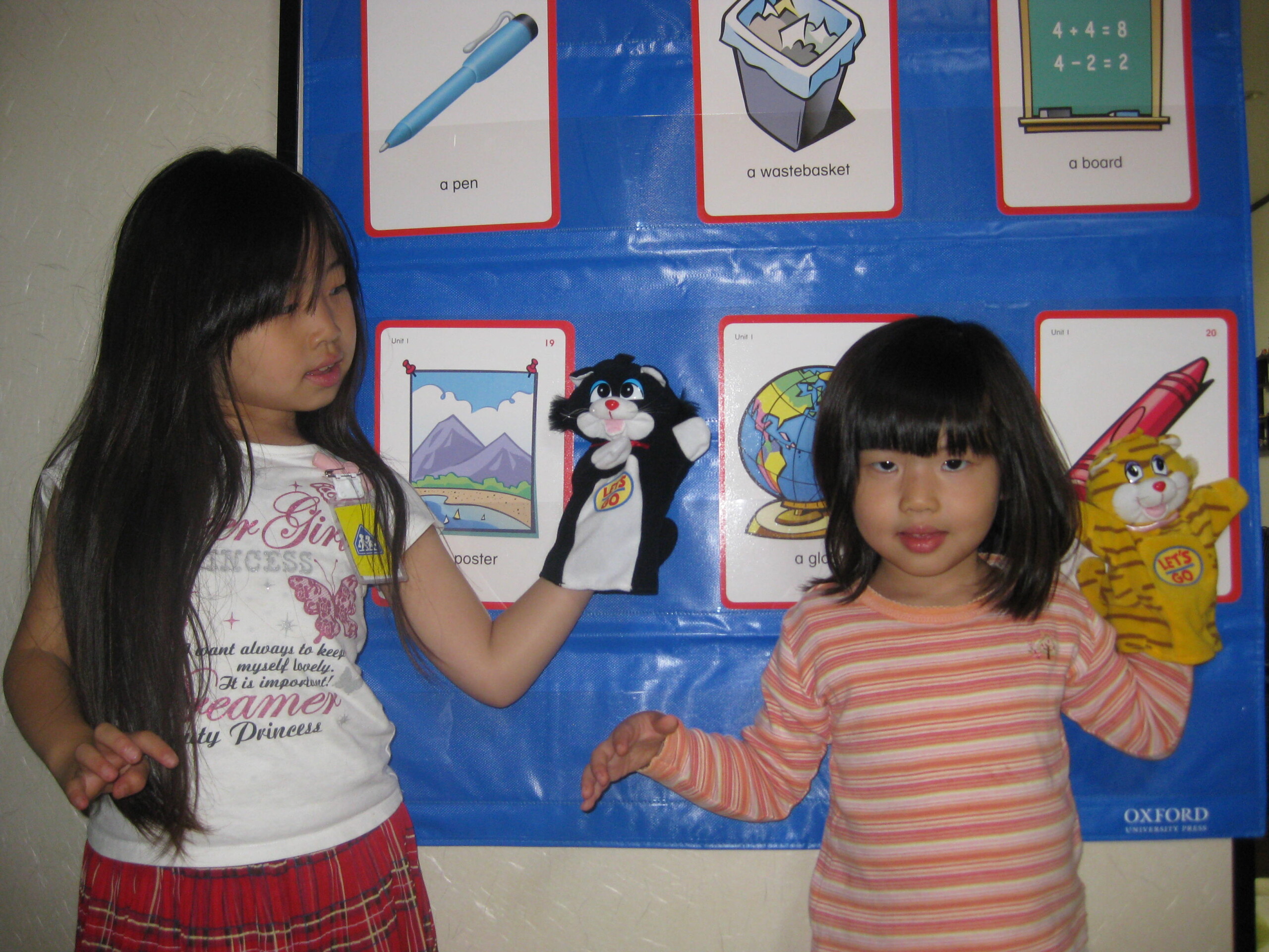 Students playing with puppets in front of pictures cards