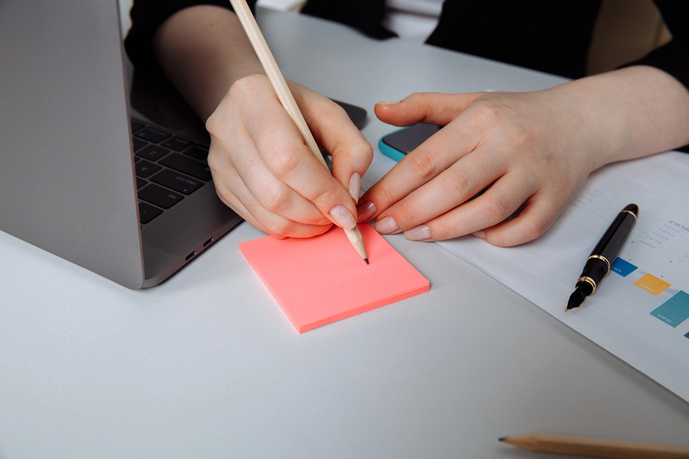 Teacher making lesson planning notes on a post-it note.