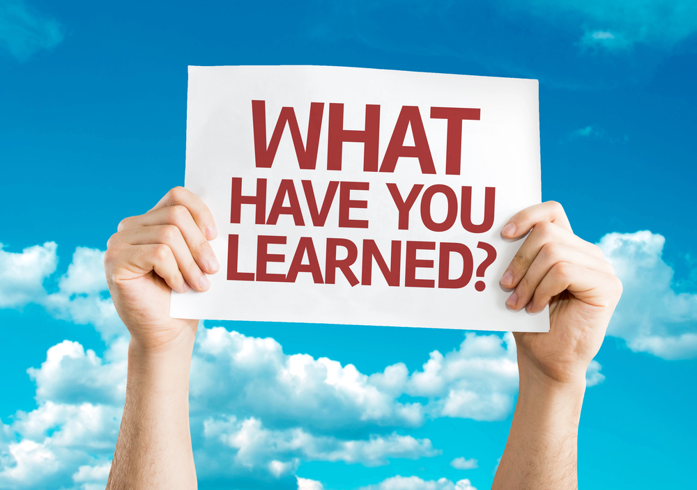 person holding a sign that says "What have you learned?"