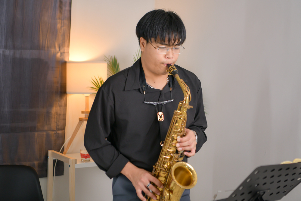 Young Asian male playing a saxophone